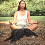 Women meditating with black lab